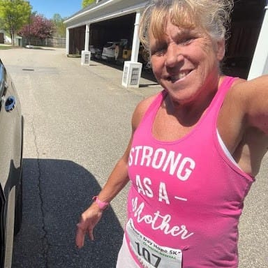 Barb taking selfie, wearing pink tank top that says "Strong as a mother"