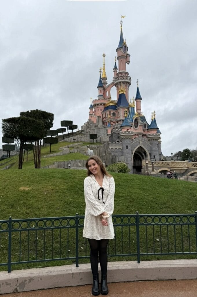 Woman smiling in front of Disneyland castle.
